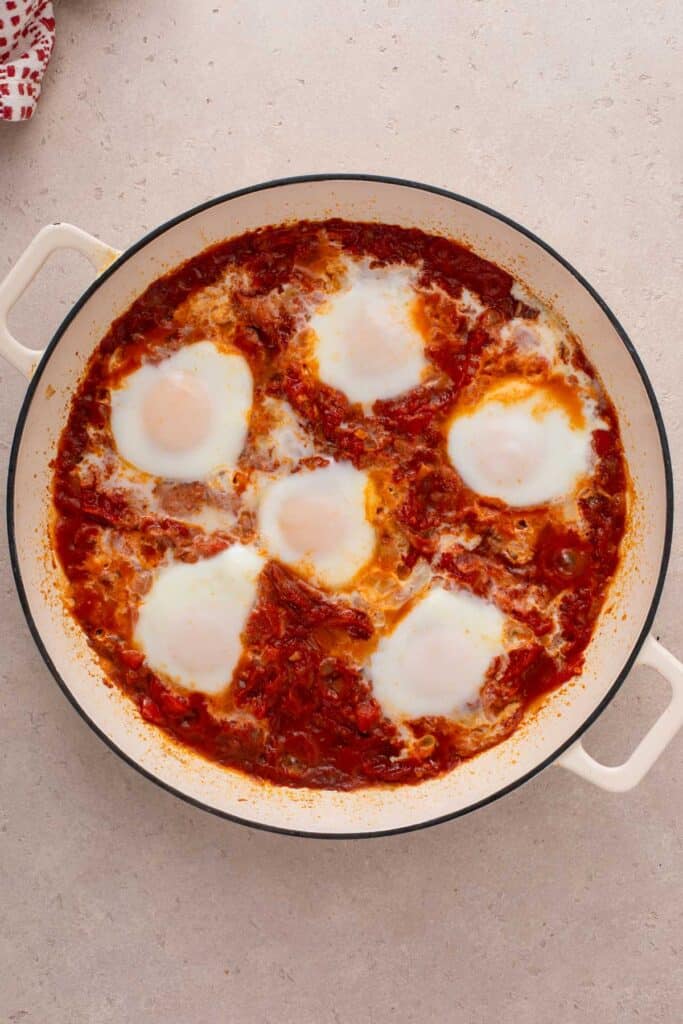 A skillet with eggs cooked in savory tomato sauce