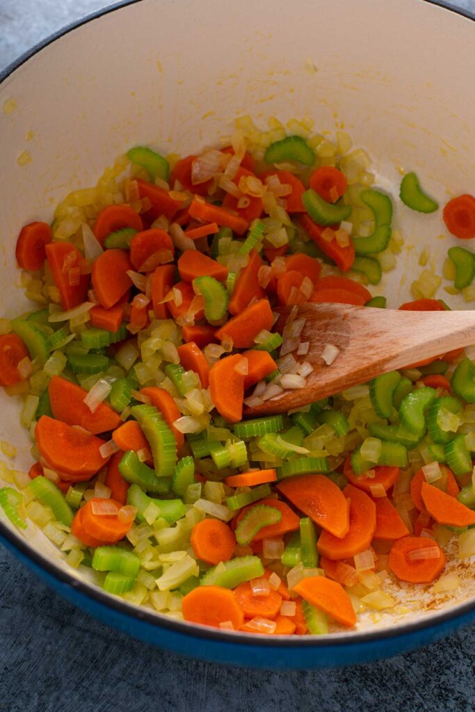 Sautéing chopped onion, carrots and celery in olive oil in a Dutch oven