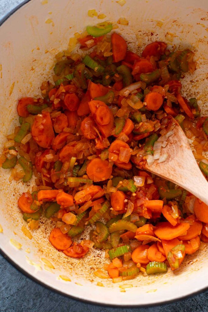 Blooming the spices and sautéing vegetables with tomato paste in a Dutch oven.