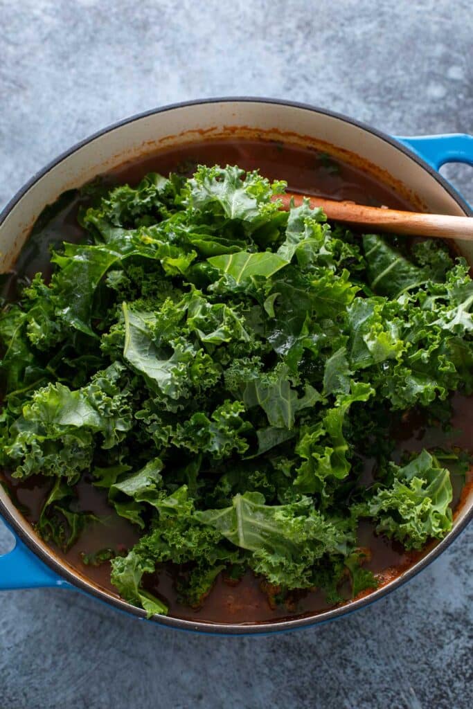 Adding kale to a Dutch oven with soup