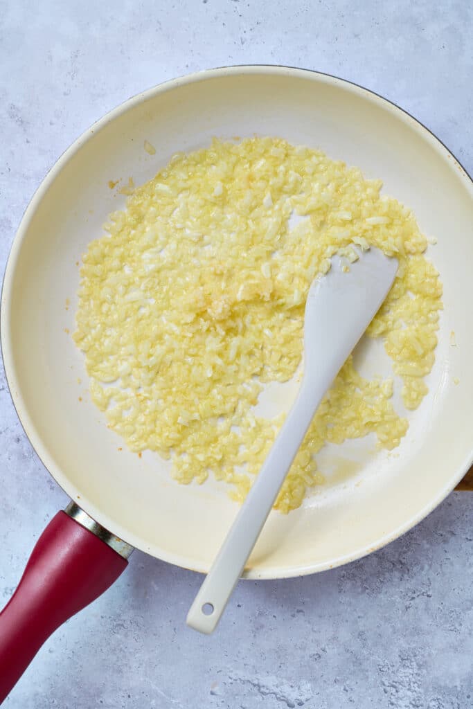 Onions and garlic sautéing in a skillet.