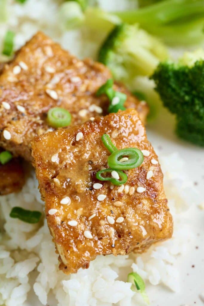 Close up image of golden brown crispy lemon pepper tofu served over rice.