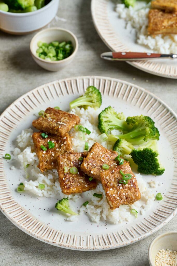 Crispy tofu with sesame seeds and lemon zest served over rice with steamed broccoli