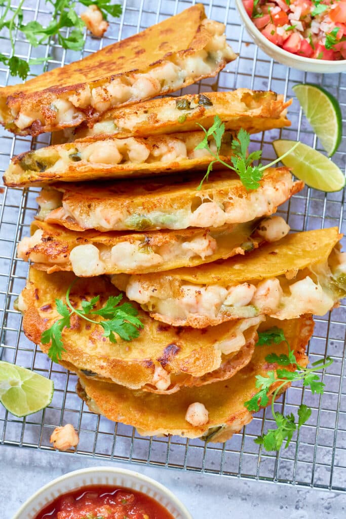 Crispy and cheesy shrimp tacos stacked on a cooling rack.