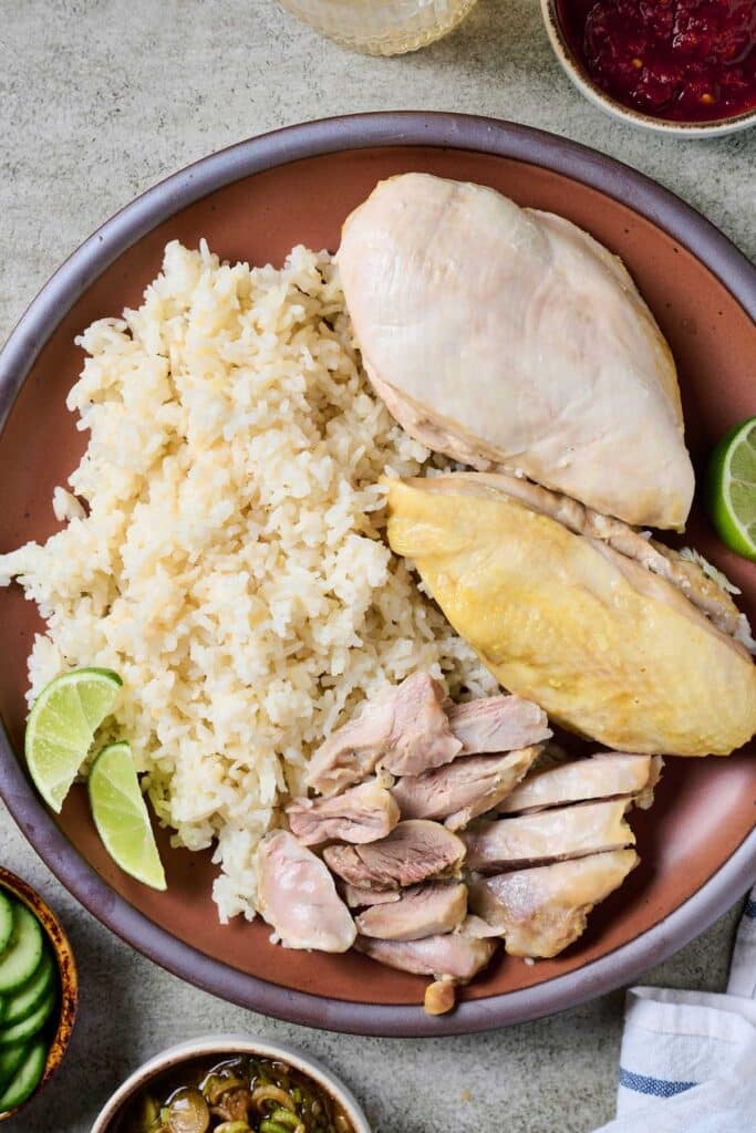 Gently poached Hainanese chicken served with rice and scallion sauce and sliced cucumbers