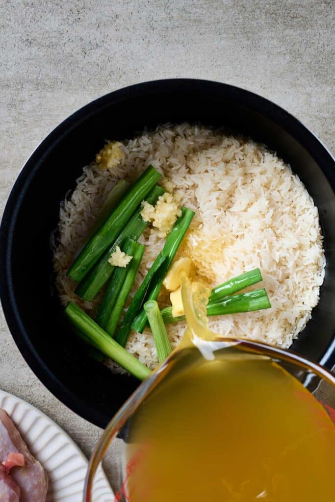Pouring broth over rice in a rice cooker