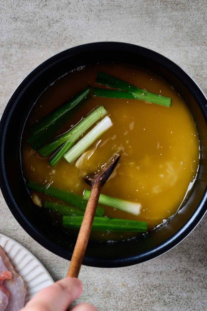 Mixing together rice, broth and aromatics in a rice cooker
