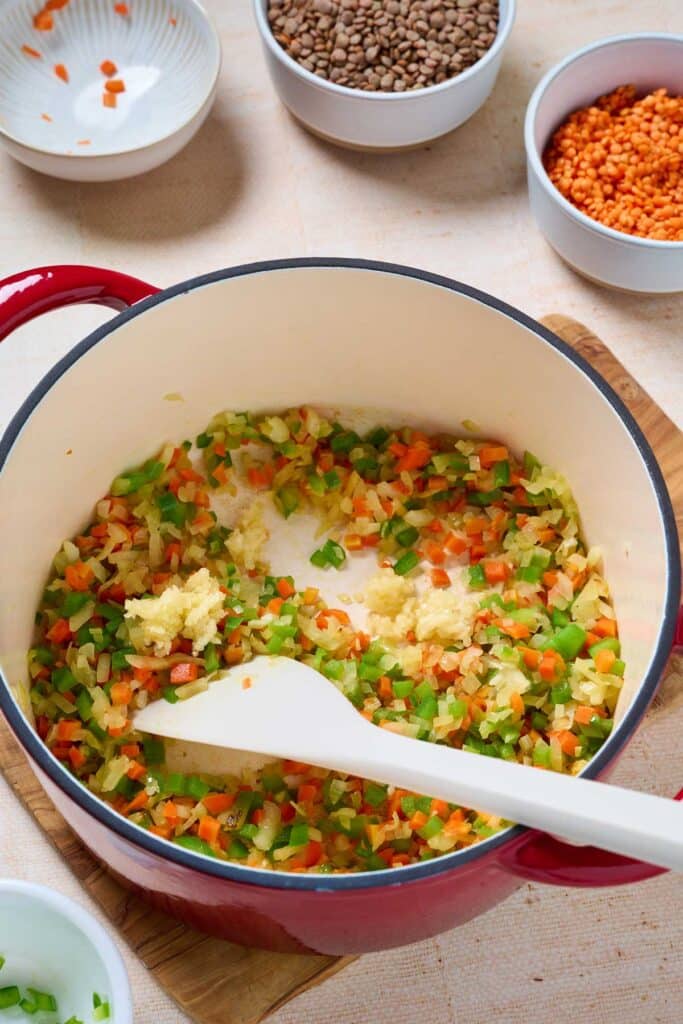Fresh minced garlic, added into a Dutch oven with sautéed vegetables.