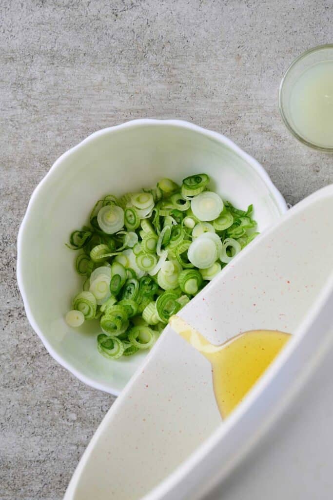 Pouring hot oil over sliced scallions