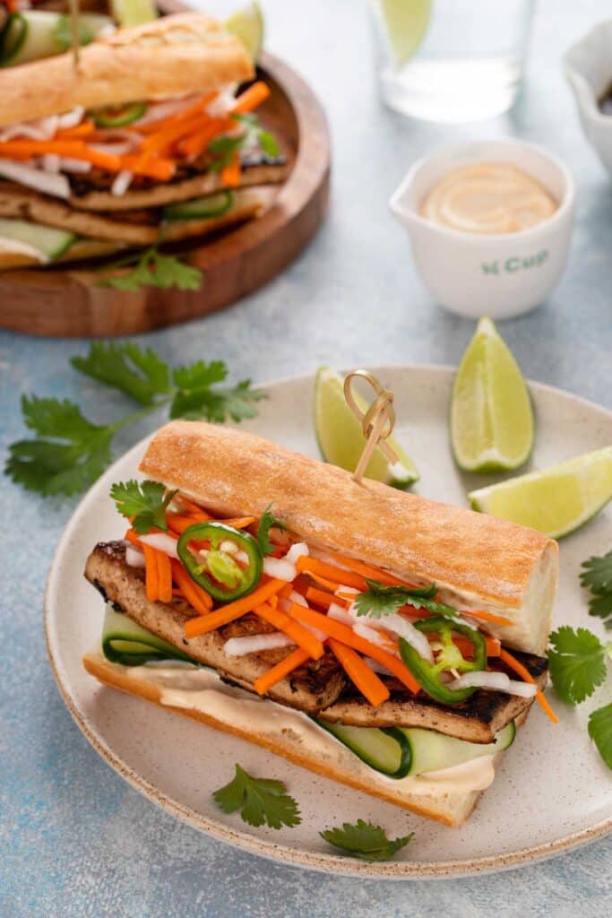 A tofu sandwich topped with pickled vegetables served on a French baguette