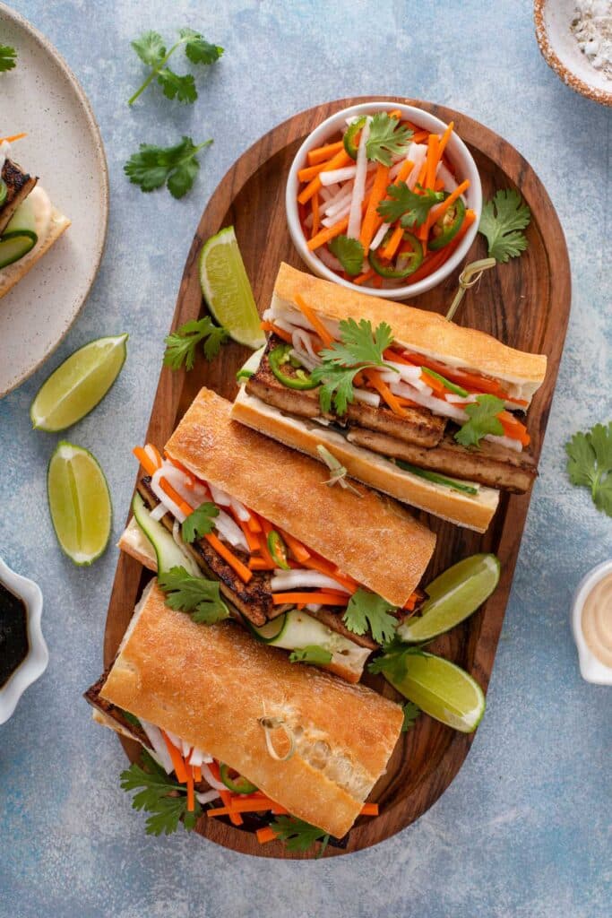 Tofu sandwiches with pickled veggies on a wooden tray