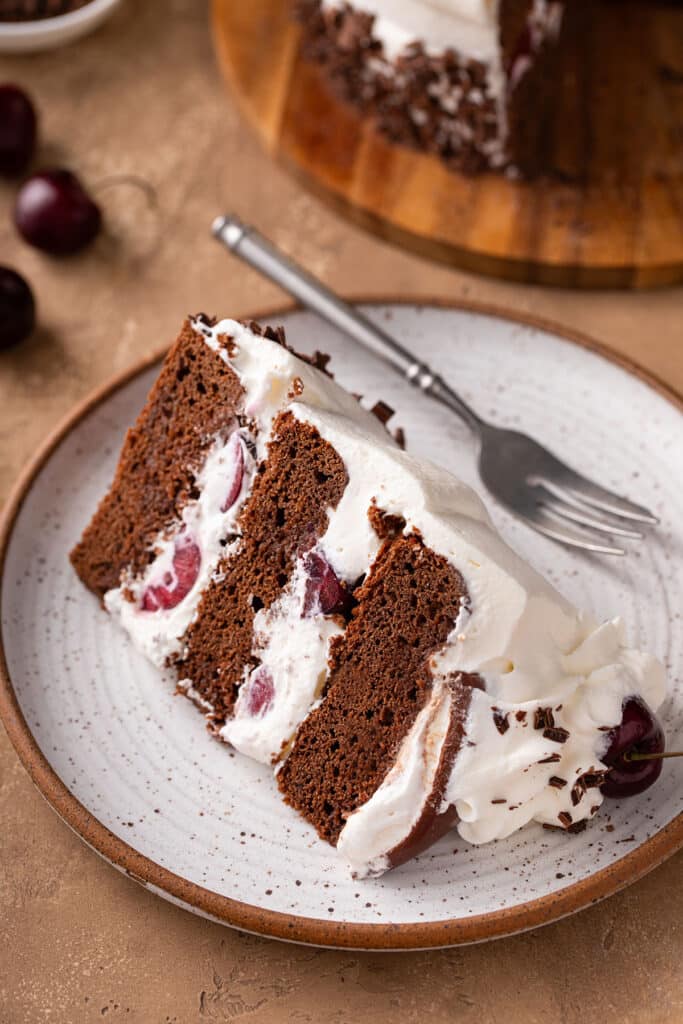 a slice of three layered Black Forest Cake on a plate