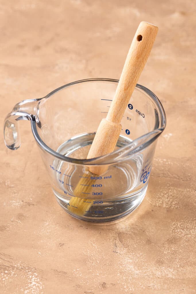 A pastry brush in a measuring cup with syrup
