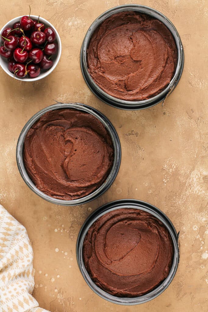 three cake pans with chocolate cake batter
