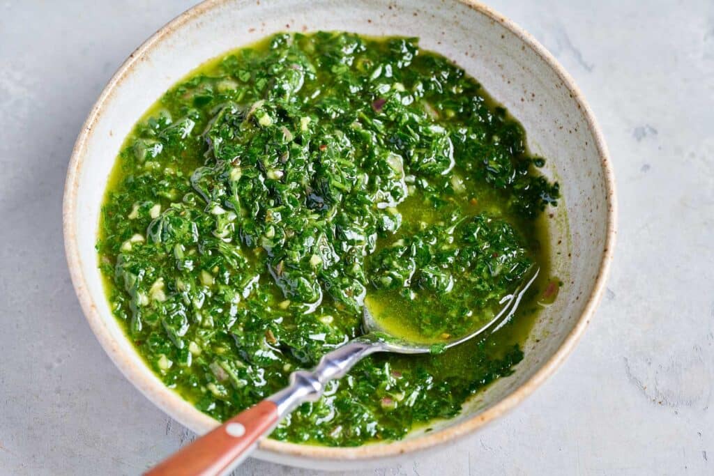 A bowl filled with chimichurri sauce.
