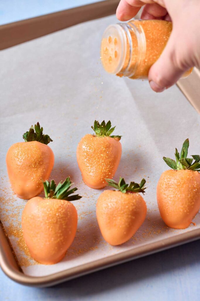 Sprinkling chocolate covered strawberries (orange candy melts) with sanding sugar