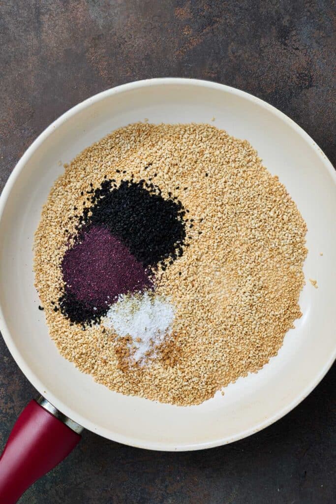 Regular and black sesame seeds and seasonings in a skillet