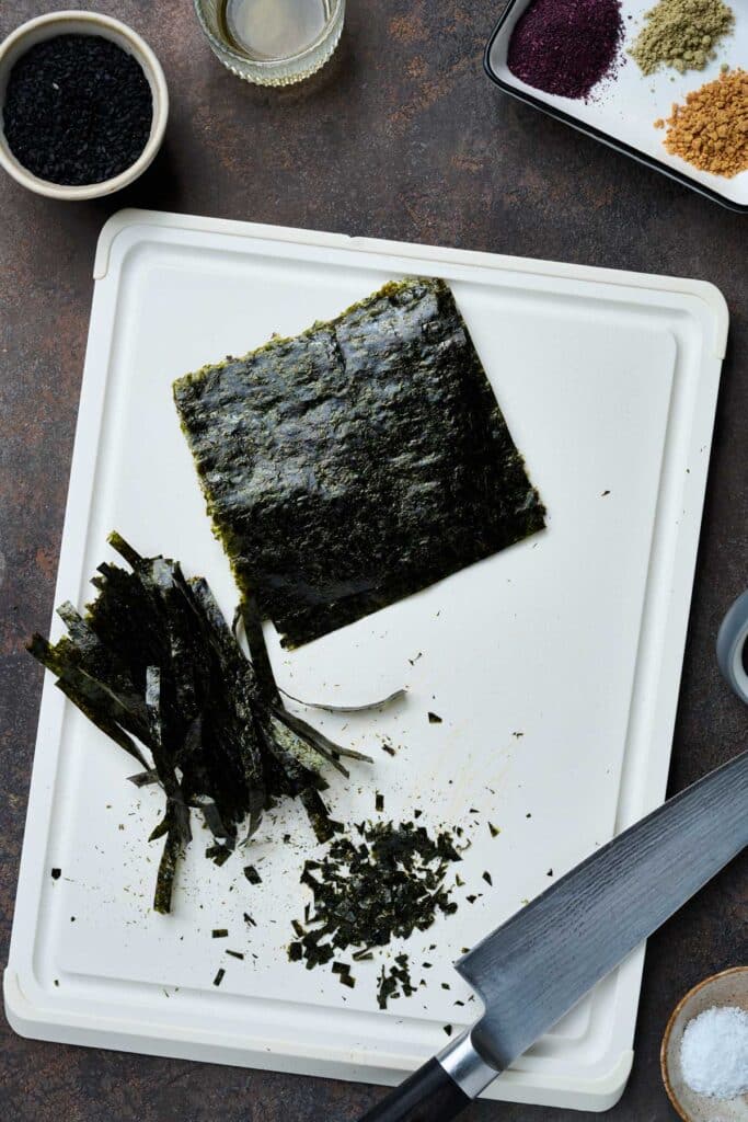 A cutting board with nori sheets and each step to cut the nori properly