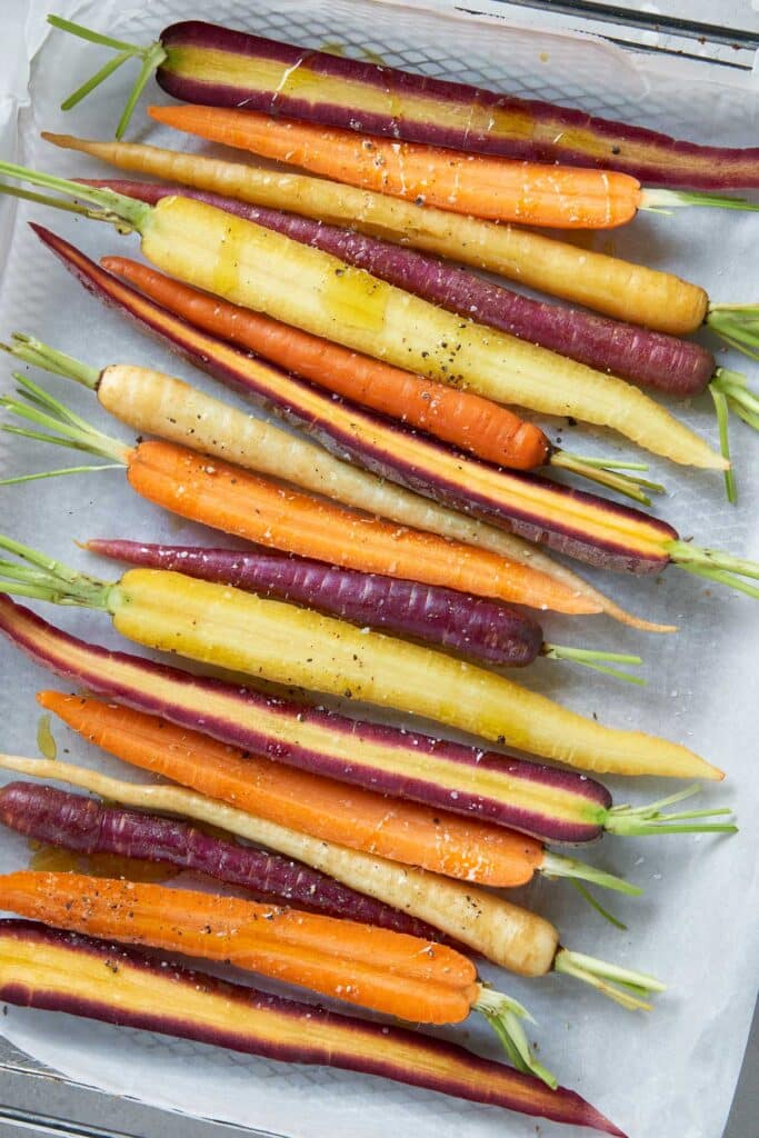 rainbow carrots seasoned on a parchment-paper lined baking pan