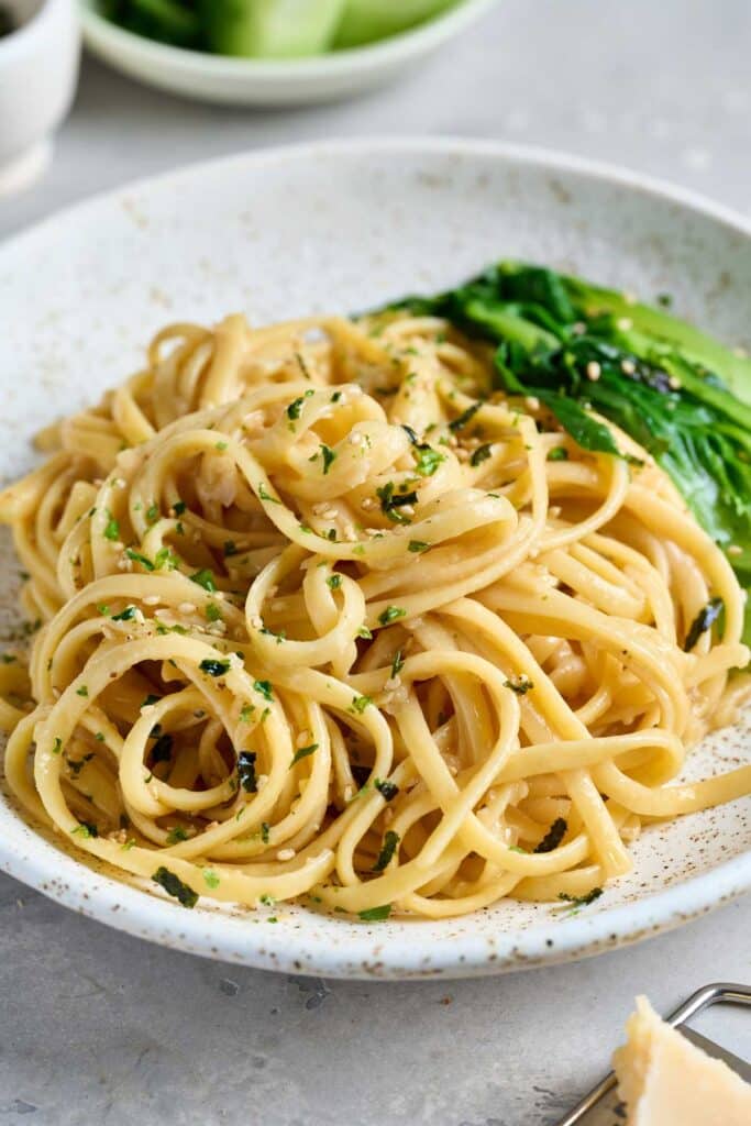 A bowl of spaghetti noodles in a simple creamy miso sauce served with bok choy and garnished with sesame seeds.