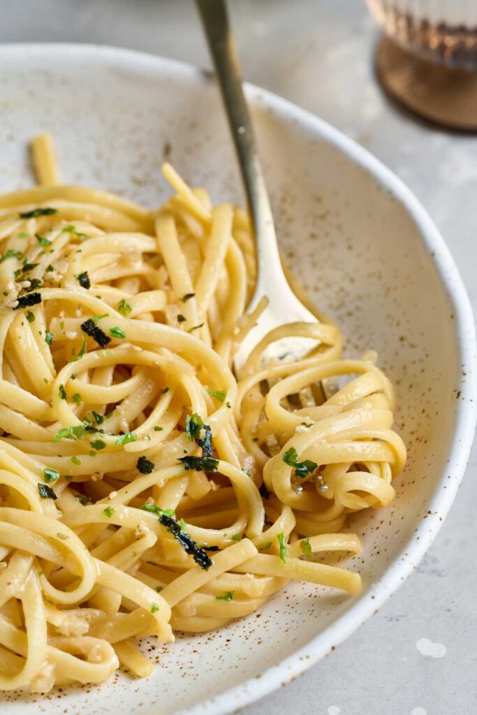 Creamy noodles in a bowl garnished with sesae seeds and furikake