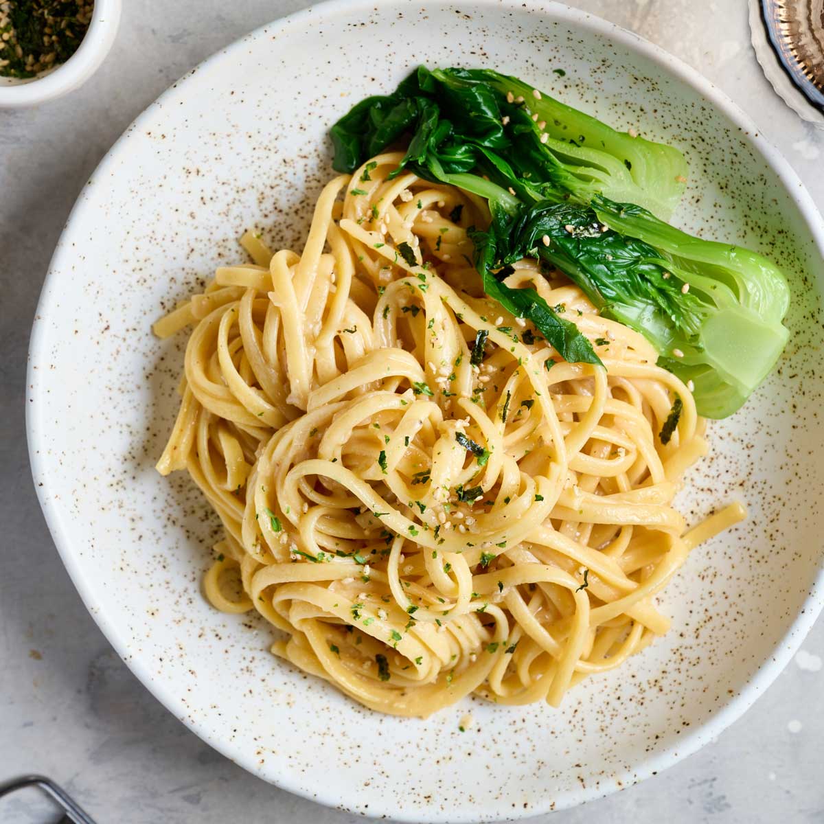 Noodles in a creamy miso sauce served in a bowl with bok choy