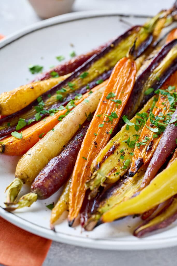 A plate of caramelized rainbow carrots garnished with chopped parsley