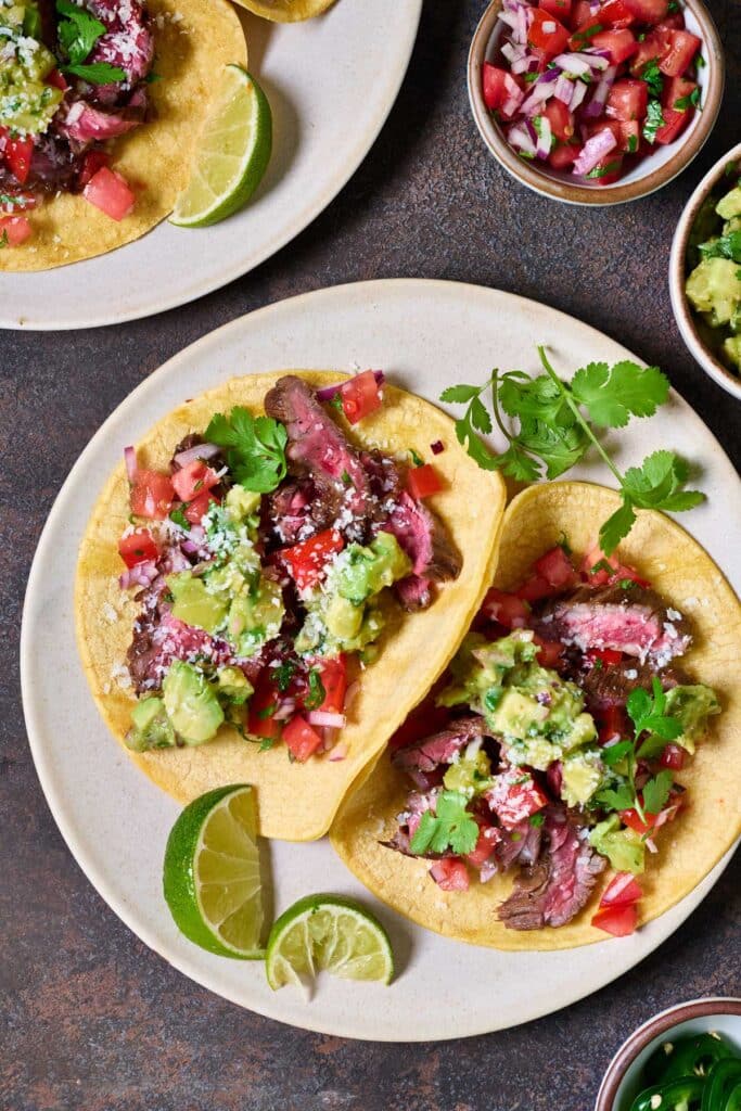 steak tacos with chopped avocados and pico de gallo on corn tortillas