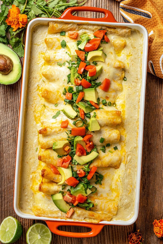 A creamy and cheesy casserole of enchiladas topped with chopped tomatoes, avocado and cilantro