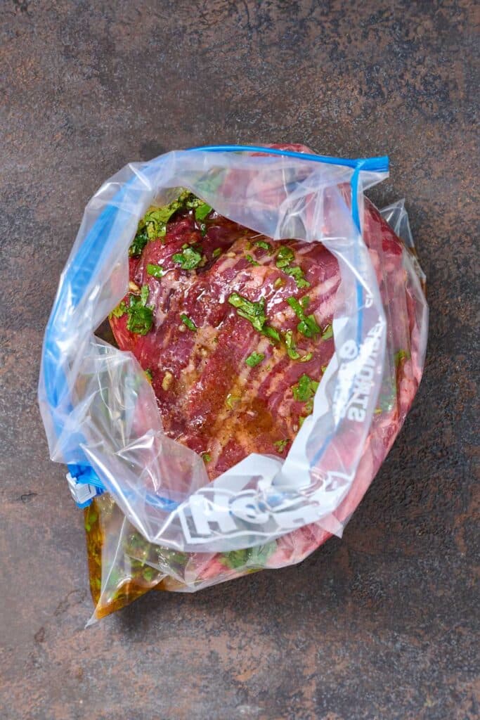 marinade poured over skirt steak inside a resealable bag