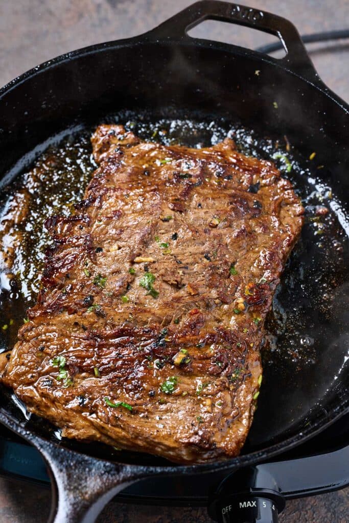Golden brown steak cooking in a cast iron skillet