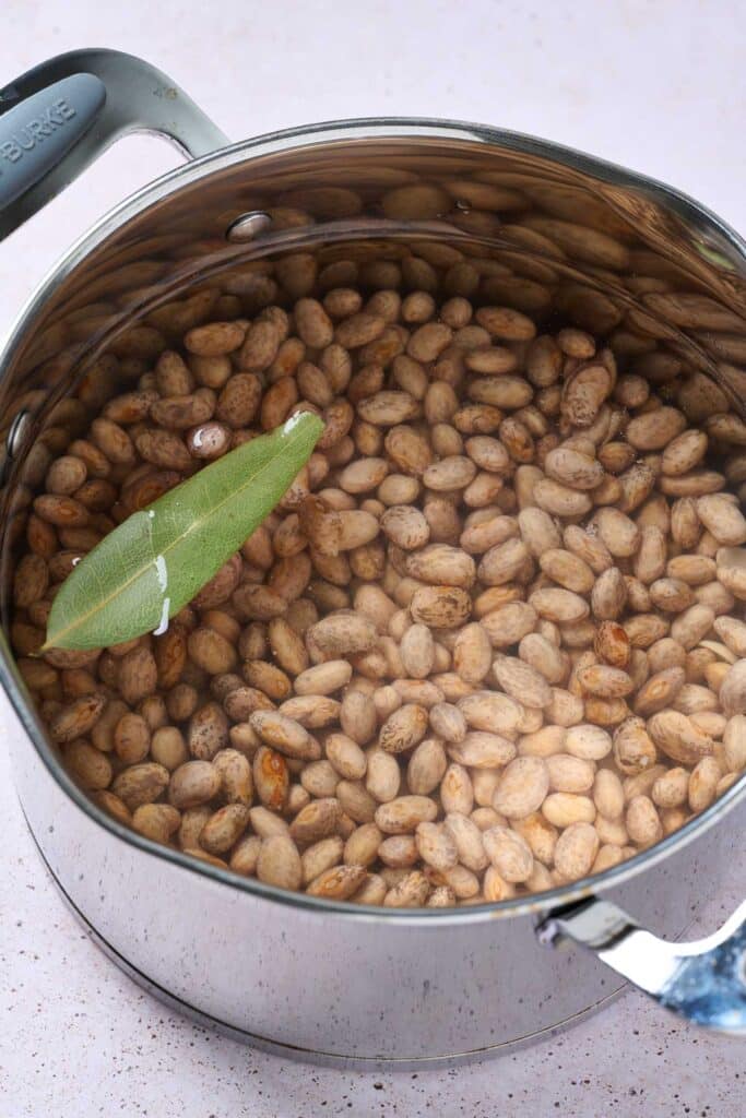 Pinto beans in a pot, covered with water with a bay leaf