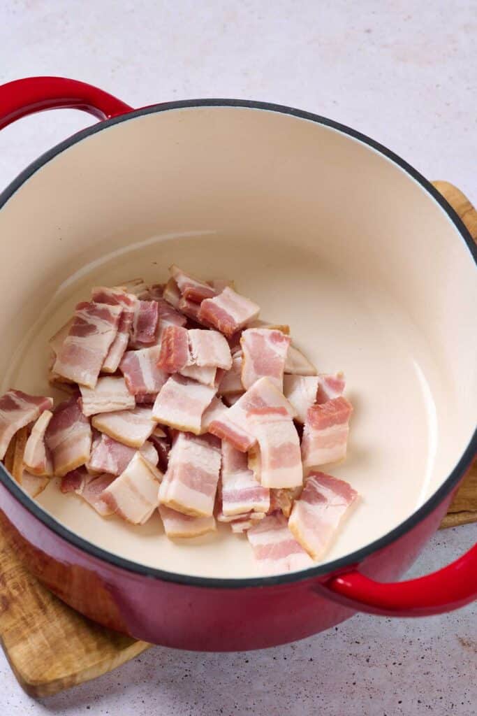 Raw bacon pieces in a Dutch oven