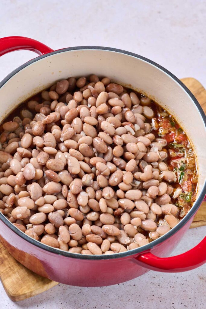 Tender pinto beans in a pot with sautéed aromatics