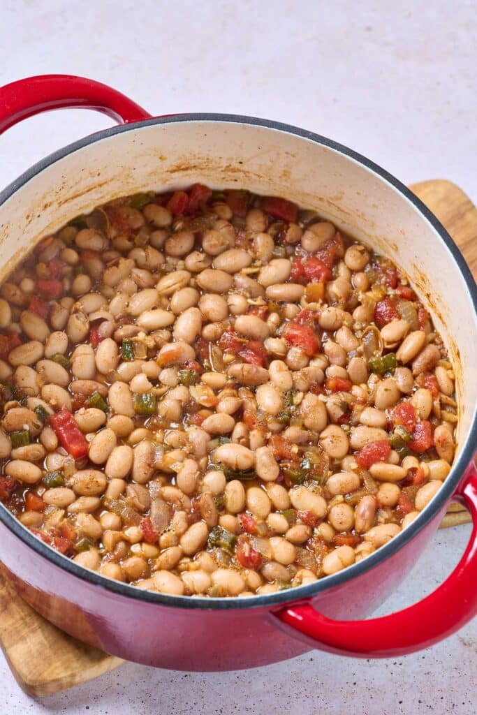 Cooked beans with chopped tomatoes and jalapenos in a Dutch oven