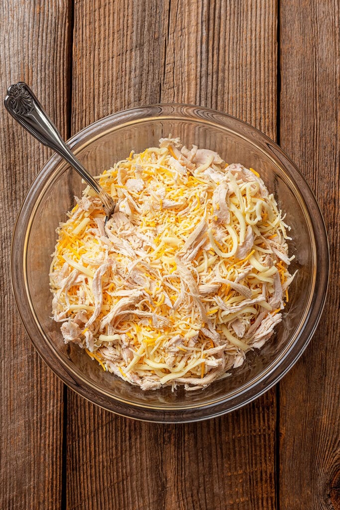 shredded chicken and cheese in a mixing bowl