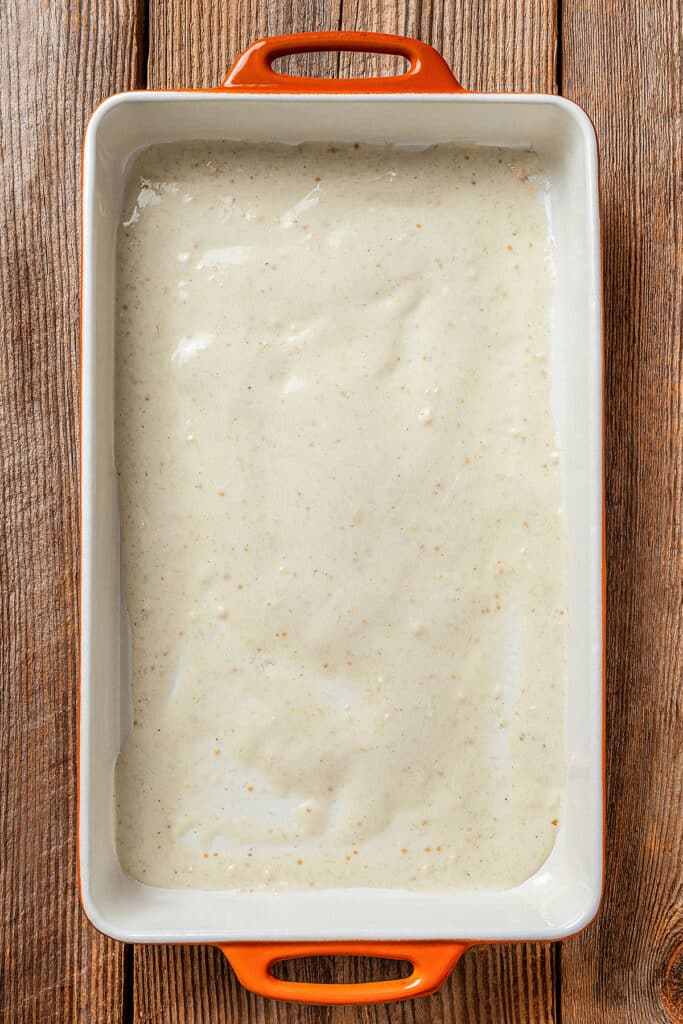 A baking dish with a thin layer of sauce at the bottom