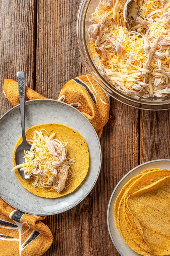 corn tortillas getting filled with a chicken and cheese mixture