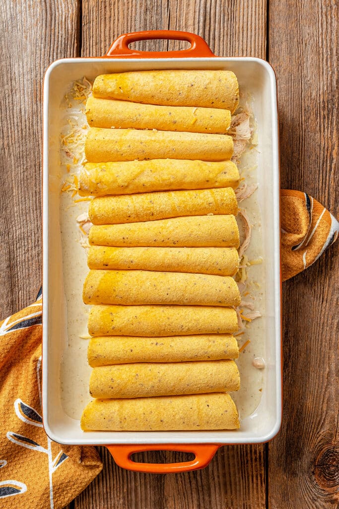 roll up corn tortillas over sauce in a casserole
