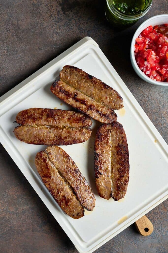 Golden brown sausages butterflied on a cutting board.