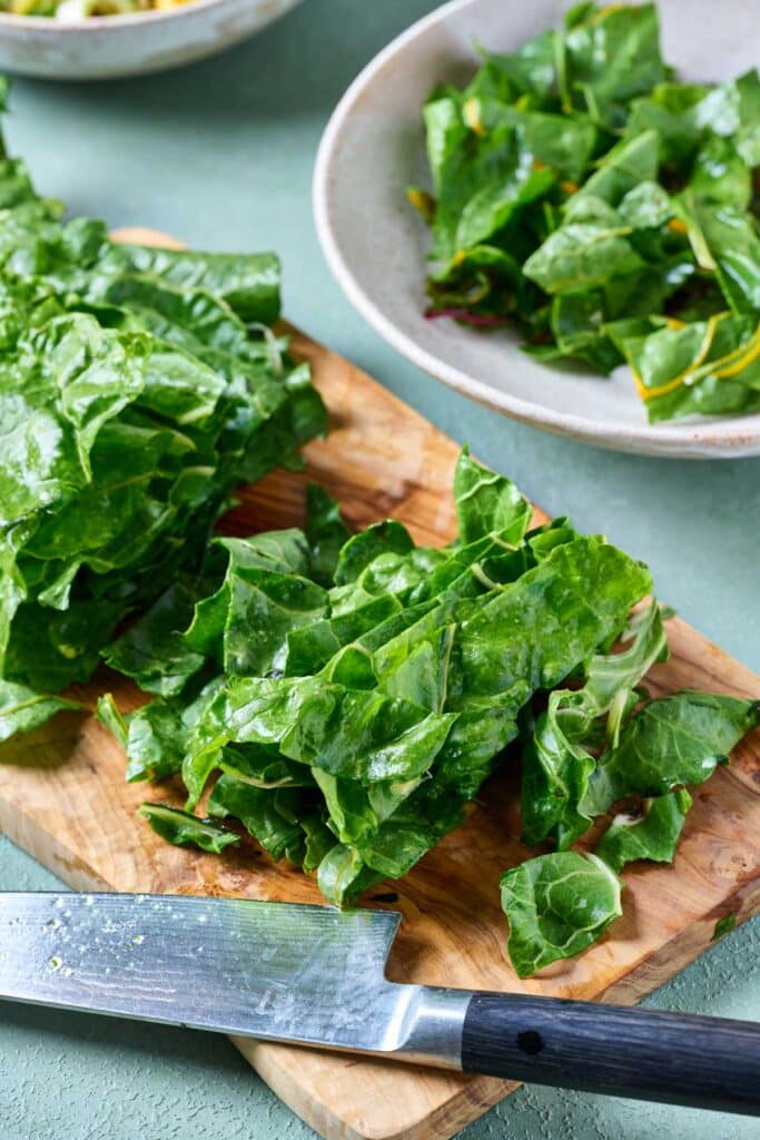 Cutting Swiss Chard leafs with a knife on a wooden cutting board