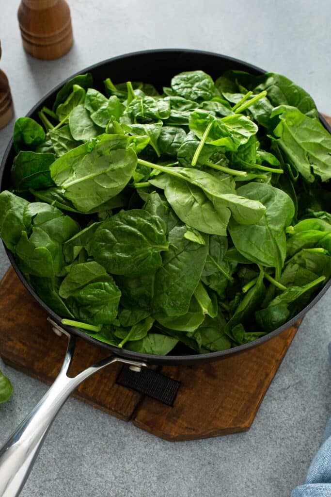 A skillet packed with baby spinach