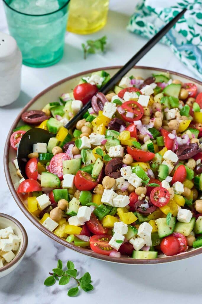 Chopped Mediterranean salad with chickpeas, tomatoes, cucumber, bell peppers, Kalamata olives and feta cheese in a salad bowl
