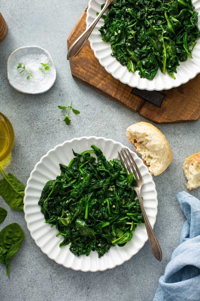 Plates with wilted bay spinach and garlic