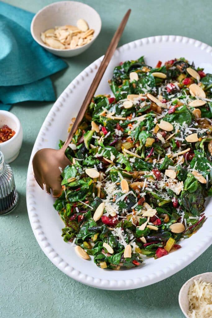 A platter of sautéed rainbow chard topped with toasted sliced almonds