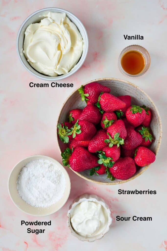 Ingredients to make cream cheese frosting and a bowl of fresh strawberries for the cake topping