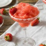 Frozen strawberry margarita served in a salt-rimmed glass with fresh strawberry garnish