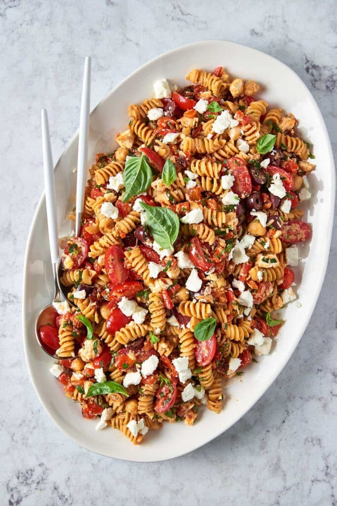 A platter with sundried-tomato pasta salad with feta cheese, tomatoes, chickpeas and feta cheese.