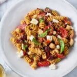 pasta salad with kalamata olives, tomatoes, feta cheese and chickpeas tossed in sun-dried tomato vinaigrette