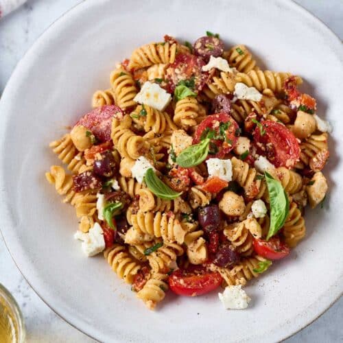 pasta salad with kalamata olives, tomatoes, feta cheese and chickpeas tossed in sun-dried tomato vinaigrette